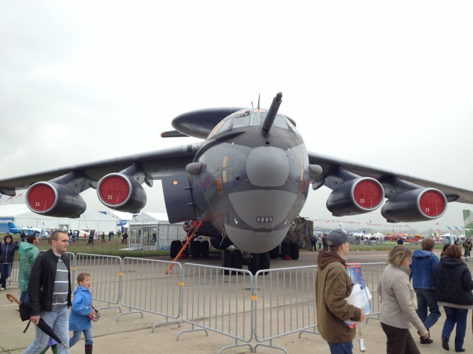 Large gray military aircraft with four engines on display at an airfield.