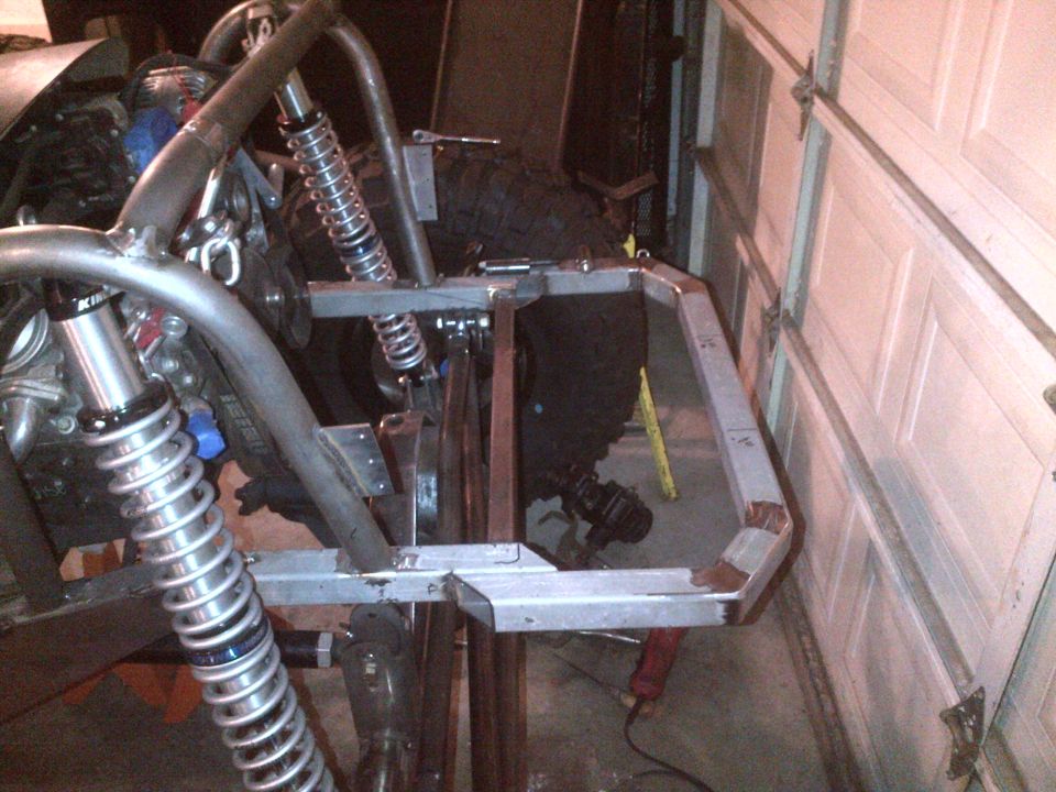 Custom metal frame with suspension parts in a garage.