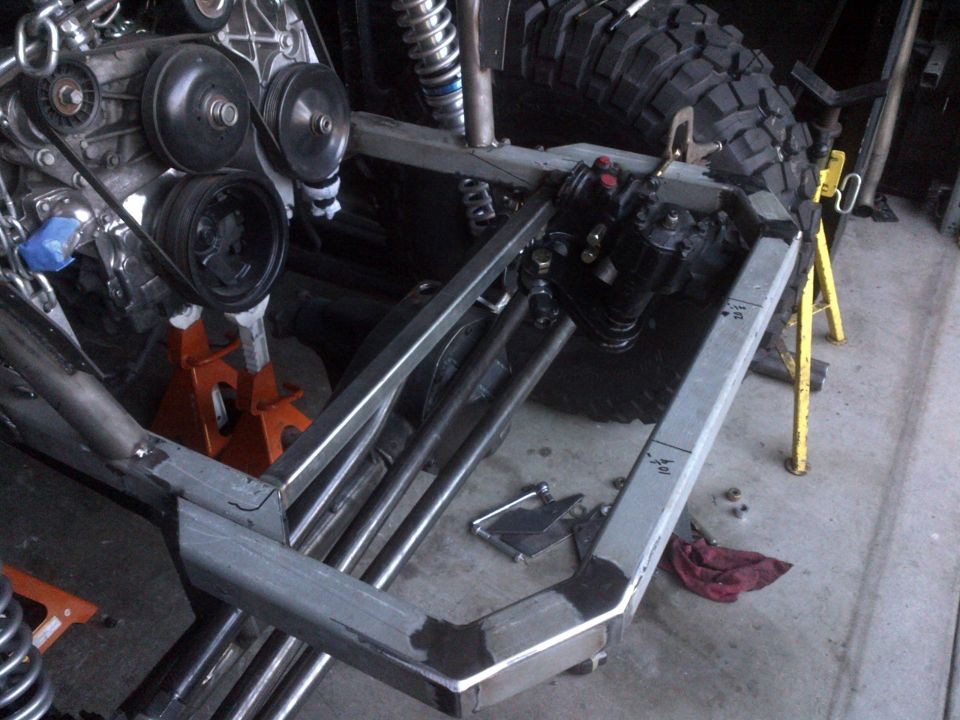 Custom off-road vehicle frame with engine, suspension, and large tire.