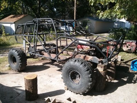 1986 Ford Bronco - A custom-built off-road buggy with a roll cage and large tires is shown outdoors, partially disassembled and supported by wooden blocks and…