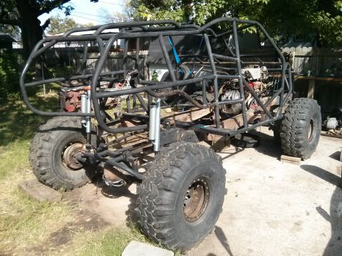 1986 Ford Bronco - A custom-built off-road buggy with a roll cage and large tires is parked outdoors on a concrete and grass surface. The vehicle appears to b…