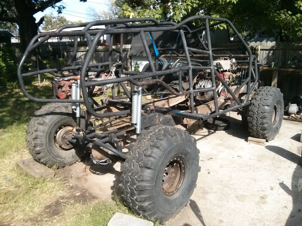 Custom off-road buggy with roll cage and large tires, under construction.