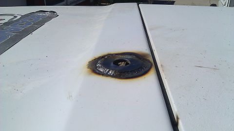 1996 Ford Bronco - A close-up view of a white vehicle's hood shows a circular metal plate that has been welded in place, with visible burn marks around the we…