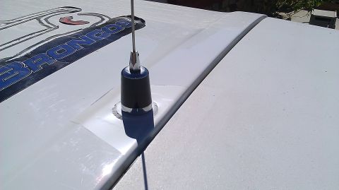 1996 Ford Bronco - A close-up view of a black and chrome antenna mounted on the roof of a white vehicle. Part of a blue and white "BRONCOS" decal is visible o…
