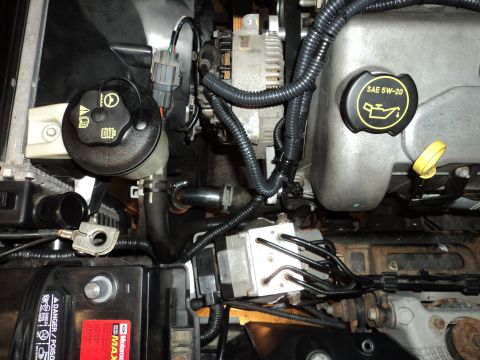 2004 Mercury Grand Marquis - A close-up view of engine components in a 2004 Mercury Grand Marquis, including the power steering fluid reservoir and the oil fill cap. Th…
