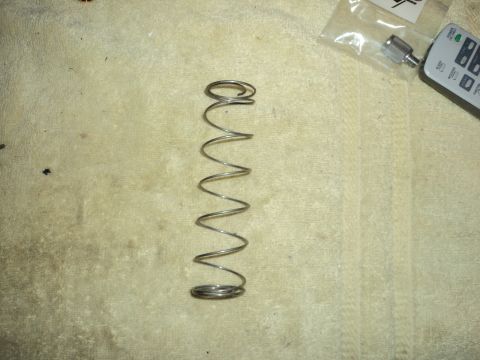 2004 Mercury Grand Marquis - A metal spring is shown lying on a textured surface. A remote control and a small plastic bag with a metal fitting are visible in the upper…