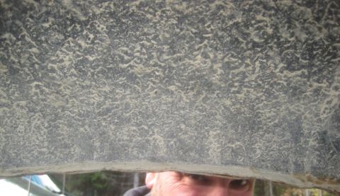 1993 Ford Bronco - Close-up view of the textured underside of a vehicle, possibly a fiberglass or composite material, with a person's face visible through a g…