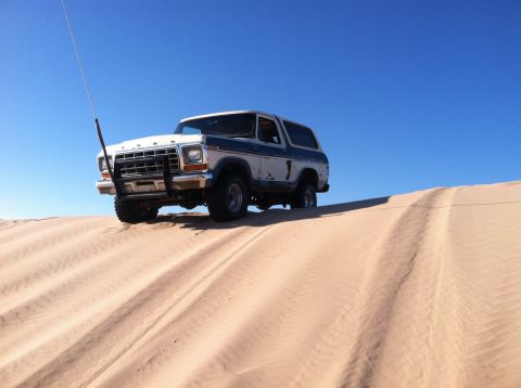 1979 Ford Bronco - Ford Bronco navigates sand dunes on a clear day.