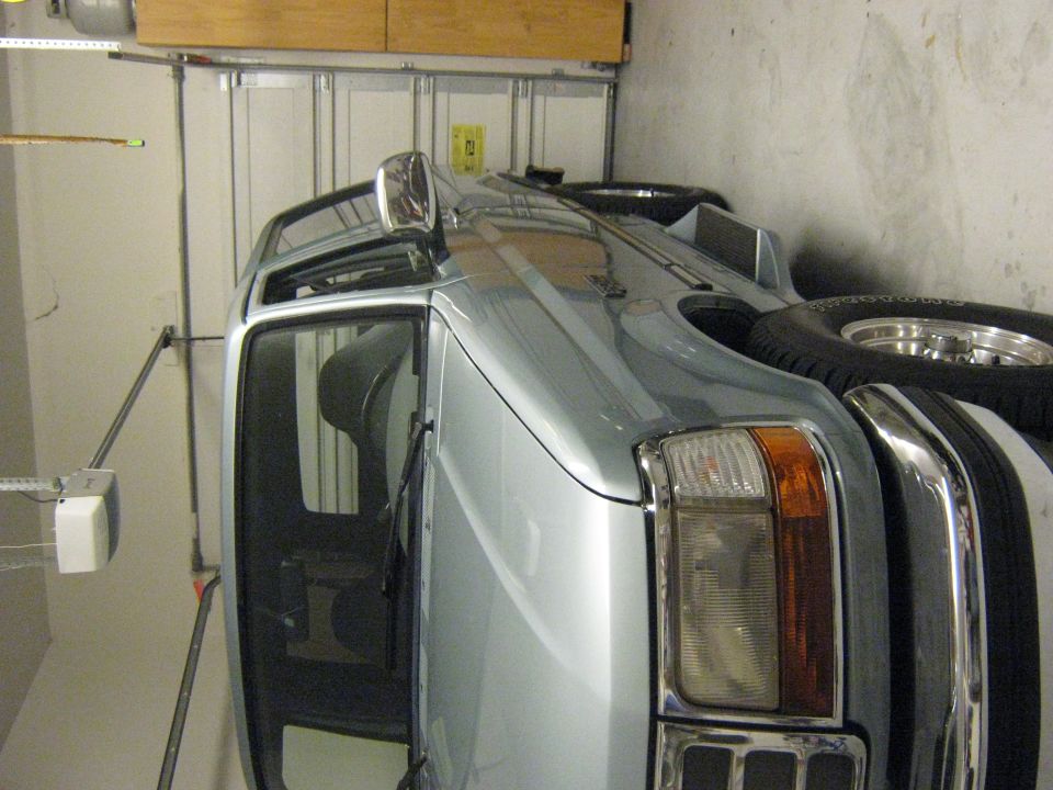 Silver SUV parked in garage, front quarter view, showing spare tire on rear