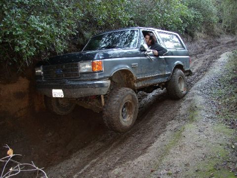 1989 Ford Bronco - A Ford Bronco navigates a challenging muddy off-road path.