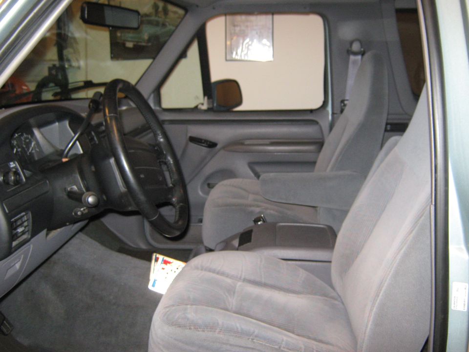 Gray fabric interior of a 1996 Ford Bronco, showing the driver's seat, dashboard, and steering wheel