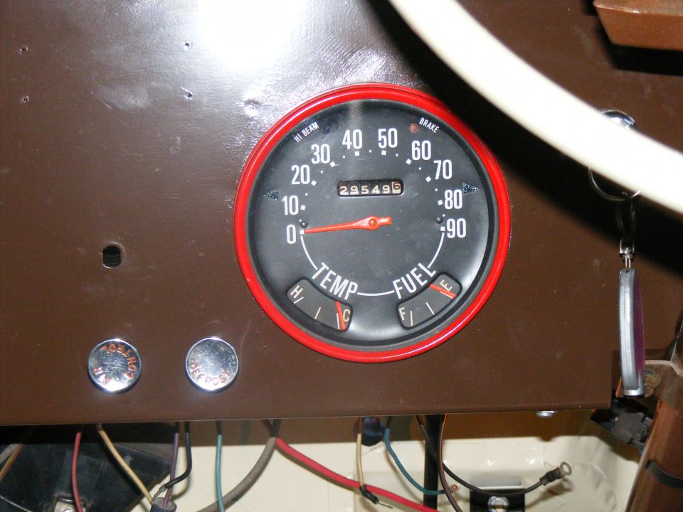 Close-up of a vehicle's dashboard with a speedometer, temperature gauge, and fuel gauge. Odometer reads 295496