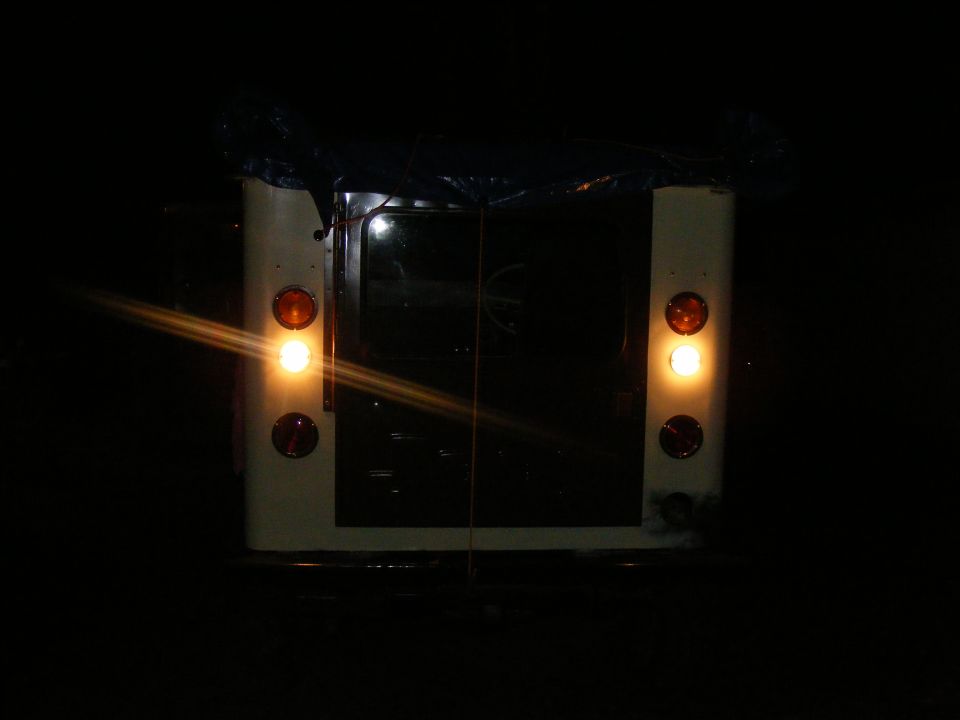 Rear view of a vehicle at night, showing taillights and brake lights illuminated