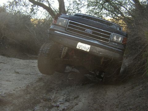 1989 Ford Bronco - 1989 Ford Bronco navigating a challenging muddy off-road path.