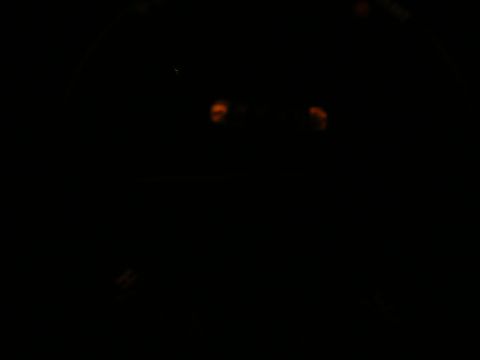 Dashboard lights glow orange in a dark vehicle interior