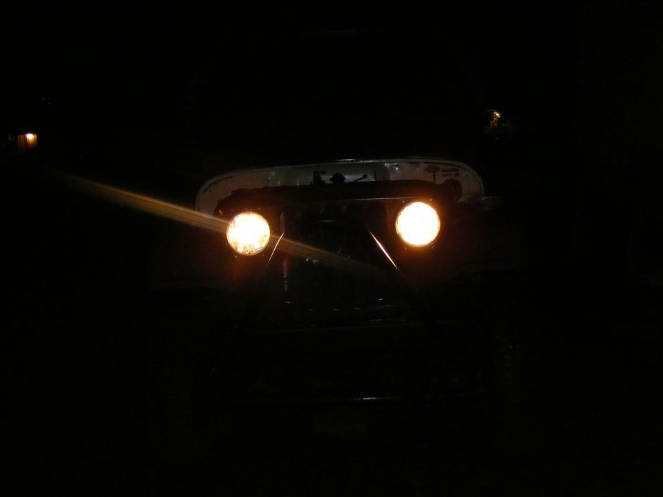 Headlights of a vehicle at night. Supermotors.net logo visible