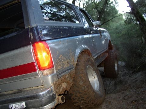 1989 Ford Bronco - This SUV is covered in mud as it navigates a difficult off-road trail.
