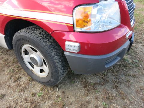 1991 Ford LTD Crown Victoria - Front corner of a red SUV with distinctive racing stripes and a close-up view of the tire and headlight assembly.