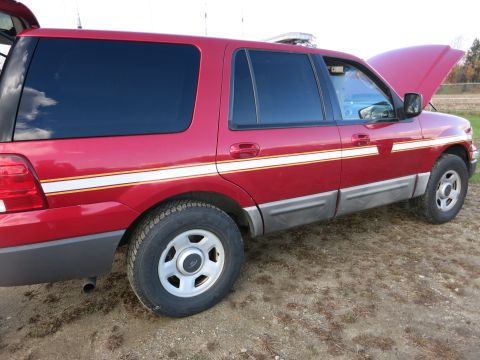 1991 Ford LTD Crown Victoria - Side view of a red SUV with tinted windows and a two-tone lower body trim.