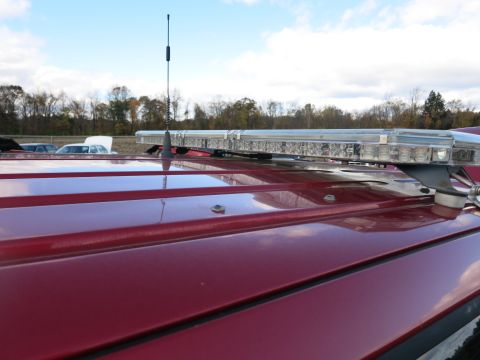 1991 Ford LTD Crown Victoria - A red vehicle's roof is shown with a light bar and antenna, with other vehicles in the background.