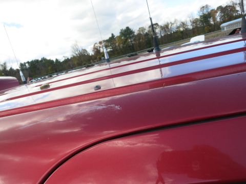 1991 Ford LTD Crown Victoria - Close-up of a red vehicle's roof, showing several antennas and a noticeable scratch on the paintwork.