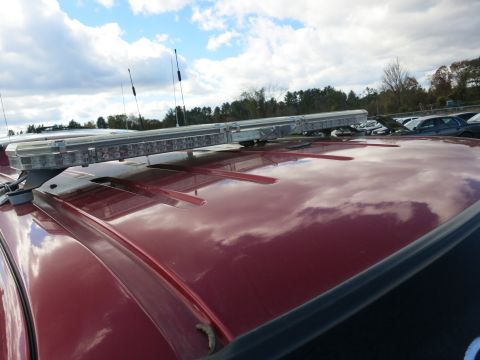 1991 Ford LTD Crown Victoria - Emergency light bar mounted on the roof of a red vehicle, with other cars in a parking lot.