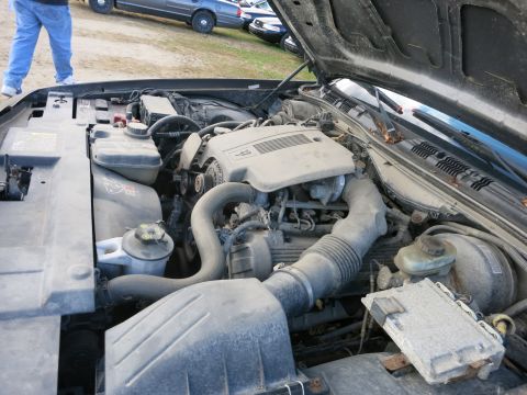 1991 Ford LTD Crown Victoria - The engine bay of a 1991 Ford Crown Victoria LTD is shown with the hood open, revealing dusty components and other vehicles in the backgrou…