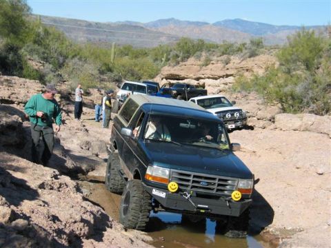 1994 Ford Bronco - A group of off-road vehicles navigate a challenging rocky terrain in a desert landscape.