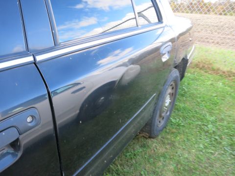 1991 Ford LTD Crown Victoria - Side view of a black sedan parked on grass with a chain-link fence in the background.