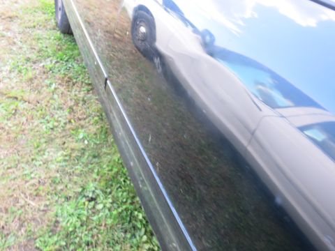 1991 Ford LTD Crown Victoria - Side view of a black car's panel, with a reflection of another vehicle and the sky visible.