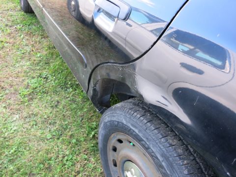 1991 Ford LTD Crown Victoria - Close-up of a black sedan's damaged rear quarter panel and wheel.