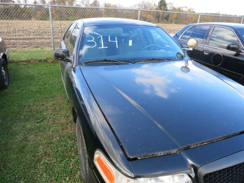 1991 Ford LTD Crown Victoria - A black 1991 Ford Crown Victoria LTD sedan is parked outdoors next to another vehicle, with a number written on its windshield.