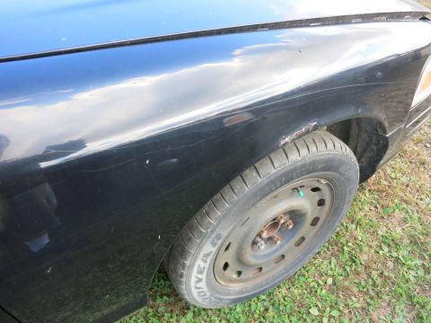1991 Ford LTD Crown Victoria - Close-up of a 1991 Ford Crown Victoria LTD's front fender and wheel, showing signs of wear and tear.