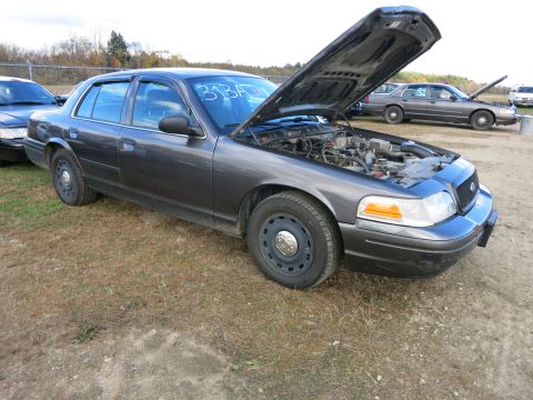 1991 Ford LTD Crown Victoria - A dark grey 1991 Ford Crown Victoria LTD sedan is parked with its hood open, revealing the engine bay. Another similar vehicle is visible i…