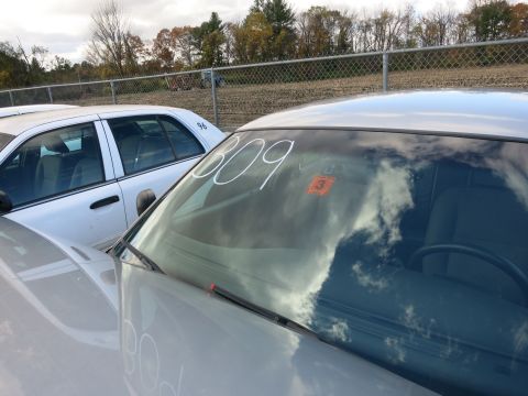 1991 Ford LTD Crown Victoria - A white sedan is parked next to another white vehicle, with the number 309 written on its windshield.