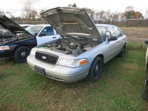 1991 Ford LTD Crown Victoria - Two Ford Crown Victoria police cars are parked outside with their hoods open.