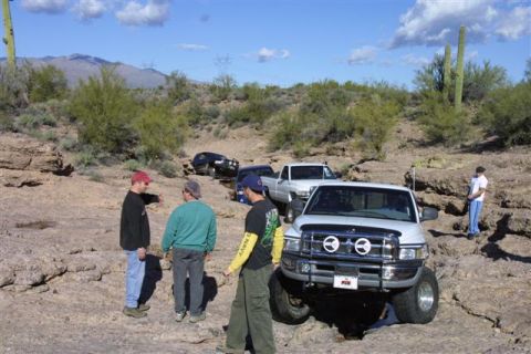 1994 Ford Bronco - Off-road vehicles gathered on a rocky desert trail with people observing the terrain.