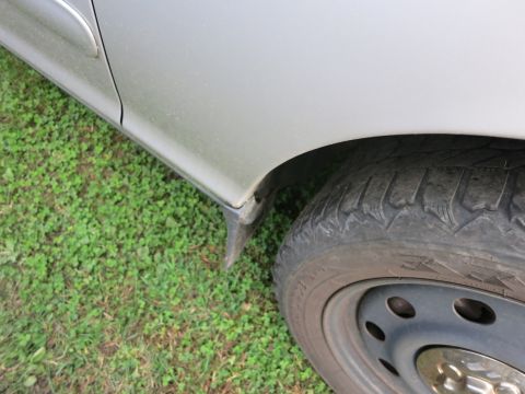 1991 Ford LTD Crown Victoria - Close-up of a silver car's fender and tire, showing the side profile against a grassy background.