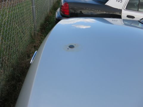 1991 Ford LTD Crown Victoria - A close-up of a car's roof shows a circular mark, with a police car visible in the background.