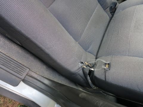 1991 Ford LTD Crown Victoria - The interior of a vehicle shows a damaged seat with frayed fabric and exposed internal components.