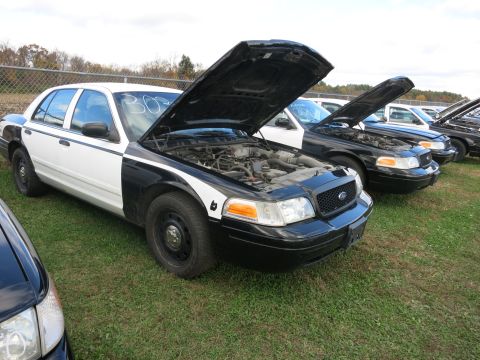 1991 Ford LTD Crown Victoria - Several police cars are lined up with their hoods open, parked on a grassy area.