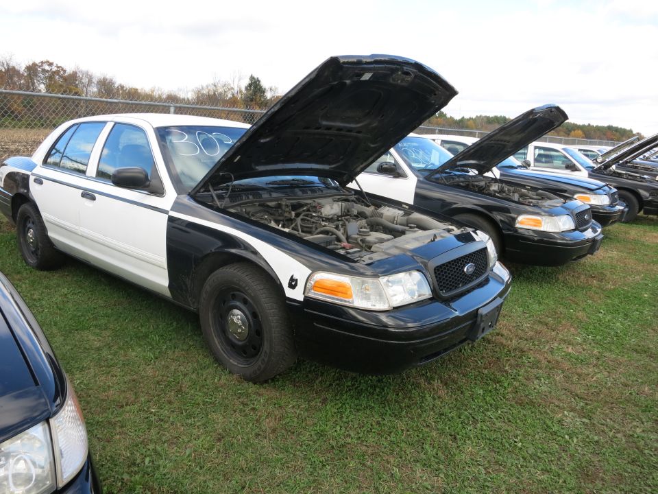 Police car with hood open, parked in a lot with other similar cars