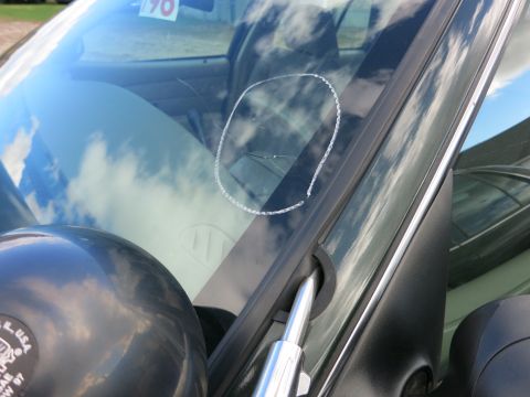 1991 Ford LTD Crown Victoria - A chalk circle highlights a crack on the windshield of a vehicle, with a '1990' sticker visible near the top.