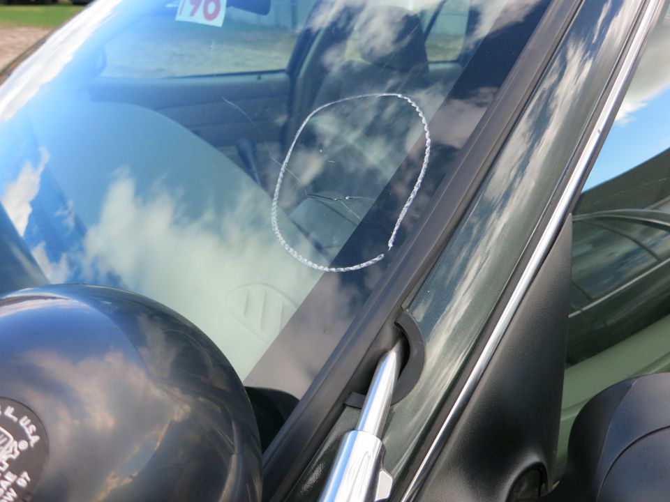 Windshield with crack circled in chalk, 1990 sticker visible