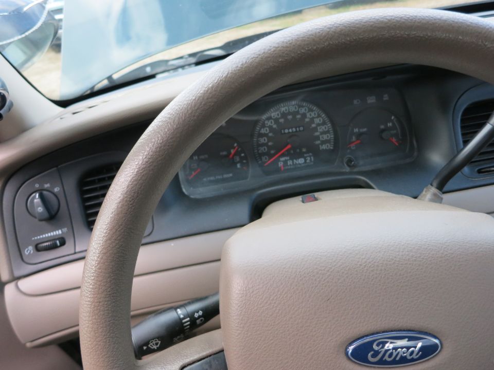 Tan steering wheel and dashboard of a car with a Ford logo. Odometer reads 104519