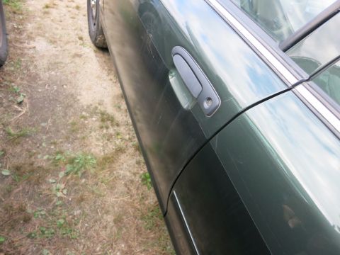 1991 Ford LTD Crown Victoria - Side view of a green car, showing the door and wheel. The paint is scratched.