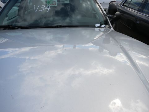 1991 Ford LTD Crown Victoria - The hood and windshield of a silver vehicle are visible, with 'V34' scrawled on the glass.