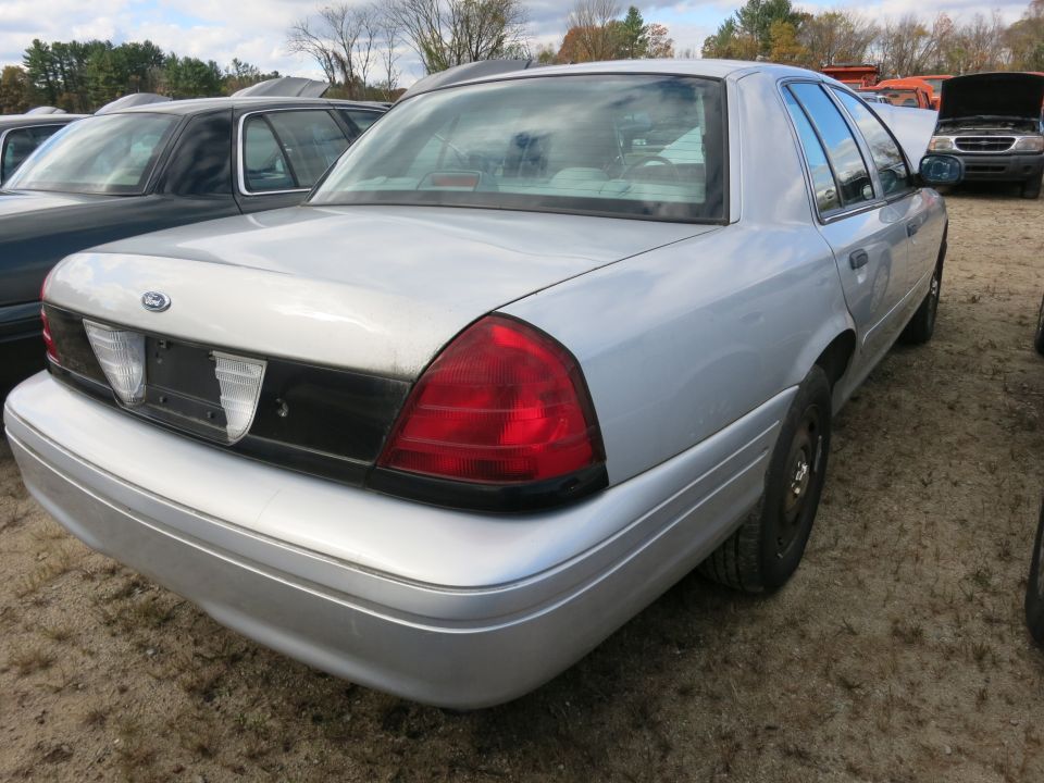 Silver sedan rear view, showing taillights, bumper, and trunk. Another car is visible to the left