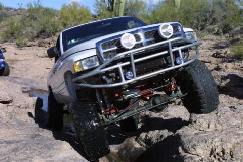 1994 Ford Bronco - A lifted Dodge Ram truck tackles a challenging off-road course with large tires and a custom front bumper.