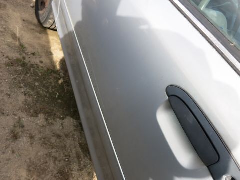 1991 Ford LTD Crown Victoria - Close-up of a silver car door and a portion of a tire.